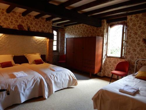 1 Schlafzimmer mit 2 Betten und einem roten Stuhl in der Unterkunft Ancien moulin atypique proche de Toulouse in Lavaur