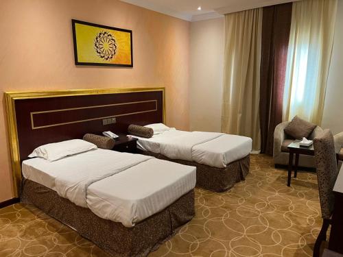 Pokój hotelowy z 2 łóżkami i krzesłem w obiekcie فندق بنيان العزيزية w Mekce