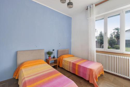 2 Betten in einem Zimmer mit Fenster in der Unterkunft La Rossa Camelia in Cannobio