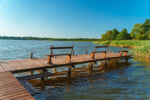 two benches sitting on a dock on a lake at Przystań Jeziorany - willa nad jeziorem - Warmia i Mazury in Jeziorany