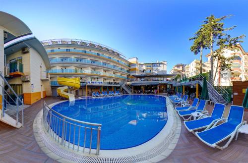 a large swimming pool in a building with blue chairs at Arsi Enfi City Beach Hotel in Alanya
