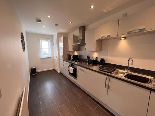 a kitchen with white cabinets and a sink at Modern 2 Bedroom Flat in Quiet Village w/ Ensuite in Bishopton