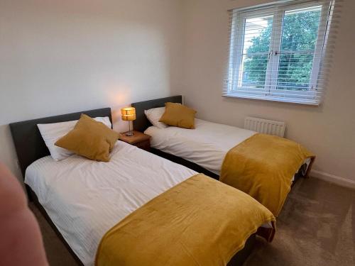 Pokój z 2 łóżkami z żółtą pościelą i oknem w obiekcie Modern 2 Bedroom Flat in Quiet Village w/ Ensuite w mieście Bishopton