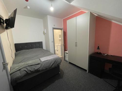 a bedroom with a bed and a dresser and a television at Luxurious En-suite Room 5 in Manchester