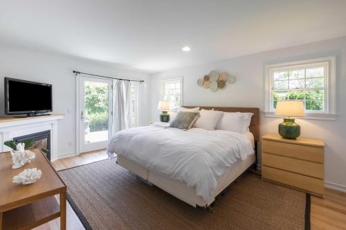 um quarto com uma cama grande e uma televisão em Heated Pool, Driftwood Cottage by RoveTravel em East Hampton