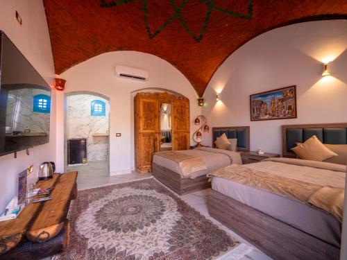 1 dormitorio grande con 2 camas y mesa en B&W SAHARA SKY CAMP, en Qasr Al Farafirah