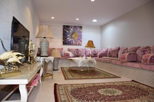 a living room with a pink couch and a table at منتجع ريف خزيمة - الفيروز in Medina