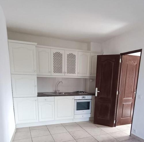 uma cozinha com armários brancos e um frigorífico preto em Appartement 1 chambre et 1 canapé-lit em Lorgues
