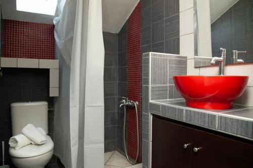 La salle de bains est pourvue d'un lavabo rouge et de toilettes. dans l'établissement Άνετο διαμέρισμα κοντά στoν Μύλο, à Tríkala