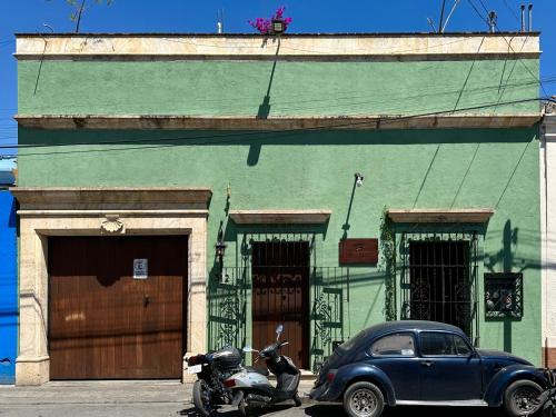 une voiture et une moto garées devant un bâtiment dans l'établissement Hostal Nordés, à Oaxaca