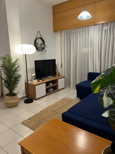a living room with a blue couch and a tv at Makenzie 2 rooms first line beach in Larnaca