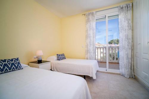 a bedroom with two beds and a window with a balcony at Arenal Park II Apartment Javea Arenal by Rock Rentals in Jávea