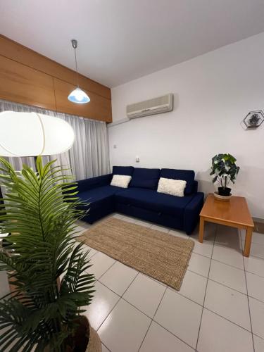 uma sala de estar com um sofá azul e uma planta em Makenzie 2 rooms em Lárnaca