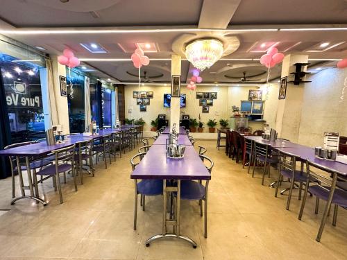 un restaurante con mesas y sillas púrpuras y globos rosas en Hotel Payal & Restaurent, en Pachmarhī