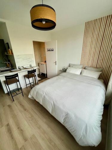 une chambre avec un grand lit blanc et une cuisine dans l'établissement L’Oliveraie, à Lille