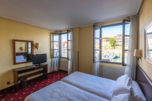 um quarto de hotel com duas camas e uma televisão em Las Rocas em Llanes