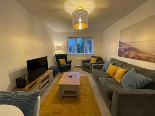 a living room with a couch and a tv at 2 bedroom luxury flat in quiet village of Bishopton in Bishopton