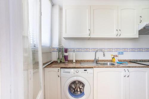 uma cozinha com uma máquina de lavar roupa e um lavatório em Javea Family Oasis: Steps from the Beach em Platja de l'Arenal