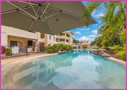 a large swimming pool with an umbrella in front of a building at Breakwater 44 in Townsville