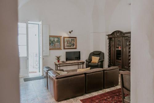 sala de estar con sofá de cuero y TV en Casa Del Tempio Antico, Salento, en Arnesano