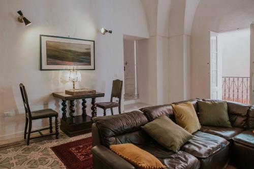 ein Wohnzimmer mit einem Ledersofa und einem Tisch in der Unterkunft Casa Del Tempio Antico, Salento in Arnesano