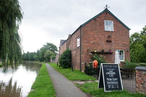 a brick building with a sign next to a canal at The Cheshire Cat by Innkeeper's Collection in Chester