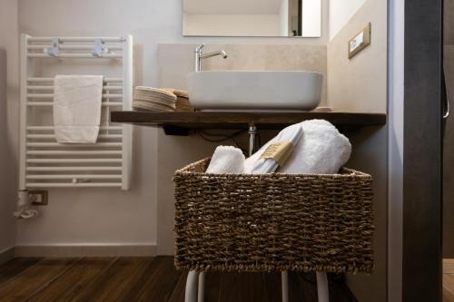 a bathroom with a sink and a basket with towels at Palazzo Gessi Room and Breakfast in Borghi