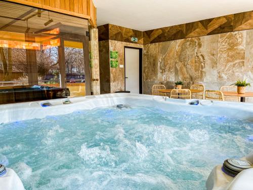 a large jacuzzi tub in a room with tables and chairs at Park Hotel Sóstó in Nyíregyháza