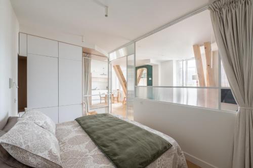 1 dormitorio con 1 cama y pared de cristal en Les Suites du Bernascon - Appartement 4 étoiles en Aix-les-Bains