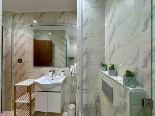 La salle de bains est pourvue d'un lavabo et d'une douche avec un miroir. dans l'établissement Bel Appart Familial Majorelle, à Marrakech