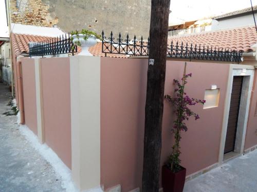 Una pared en una calle con una valla y un árbol en Sole Apartments - near Corfu Port en Ágios Rókkos