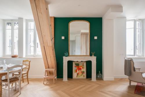 une salle à manger avec un mur vert et un miroir dans l'établissement Les Suites du Bernascon - Appartement 4 étoiles, à Aix-les-Bains