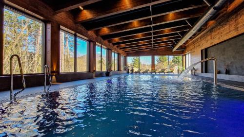 a swimming pool in a building with windows at Rezort Drevenice Terchova in Terchová