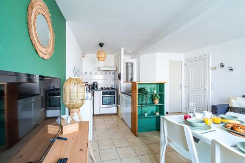 - une cuisine avec une table et un mur vert dans l'établissement Appart'Hotel NuiteeJour Versailles Saint Cyr l'Ecole, à Saint-Cyr-lʼÉcole