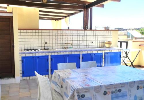 a kitchen with blue cabinets and a table and chairs at Casa Laura in San Vito lo Capo
