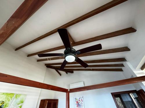 a ceiling fan in a room with wooden beams at Ciel y Miel in Colón