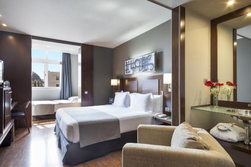 um quarto de hotel com uma cama grande e duas cadeiras em Acta Atrium Palace em Barcelona