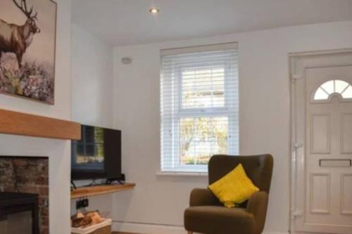 a living room with a chair and a fireplace at Beautiful renovated cottage in Mersham Ashford Kent in Mersham