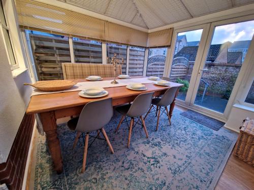 a dining room table with chairs and a large window at Stylish house centrally located in Bury Saint Edmunds