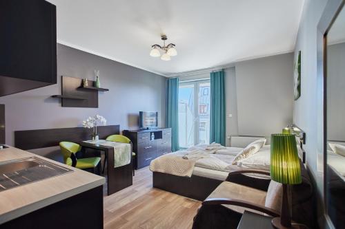 a bedroom with a bed and a desk and a table at Pegaz Apartments by Baltic Home in Świnoujście