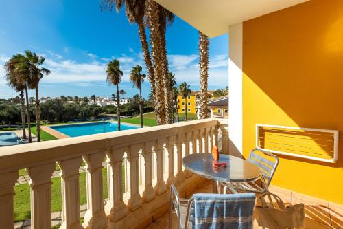 balcón con mesa, sillas y piscina en Vibra Blanc Palace Aparthotel, en Sa Caleta
