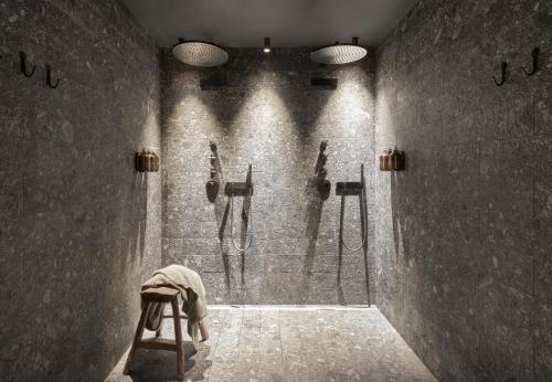 a person sitting on a stool in a room with showers at CERVO Mountain Resort in Zermatt