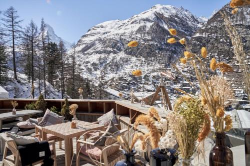 a patio with tables and chairs and a snow covered mountain at CERVO Mountain Resort in Zermatt