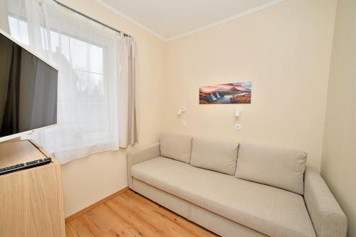 a living room with a couch and a large window at Palmy Apartmanhouse Maglód in Maglód