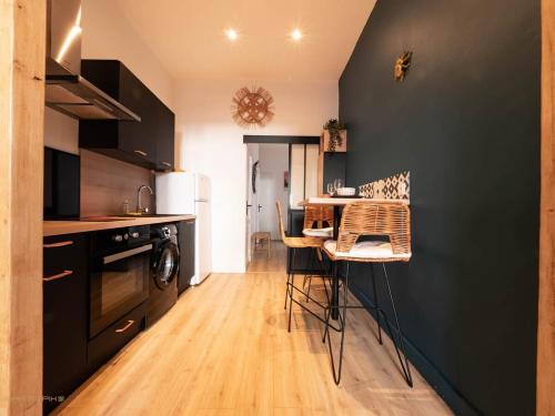 une cuisine avec des armoires noires et une table avec des chaises dans l'établissement La coquille - terrasse et climatisation en centre ville - gare Saint Roch, à Montpellier