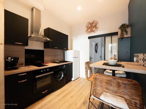 une cuisine avec des armoires noires et une table avec des chaises dans l'établissement La coquille - terrasse et climatisation en centre ville - gare Saint Roch, à Montpellier