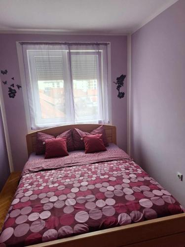 a bedroom with a large bed with red pillows and a window at Lovely L home BN centar -Rent a car automatic in Bijeljina