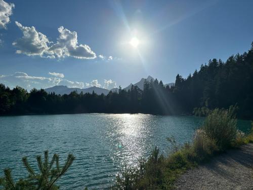 a lake with the sun shining on the water at Cityapartments Reutte in Reutte