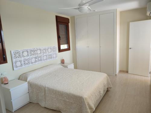 - une chambre blanche avec un lit et une fenêtre dans l'établissement Apartamento Panoramica Golf, à Sant Jordi