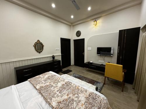 a bedroom with a bed and a desk and a television at Chaitali The Villa in Shānti Niketan